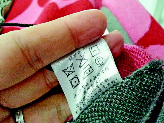 ◥吕女士购买的羊毛衫内标上,标注着不能水洗等标志.