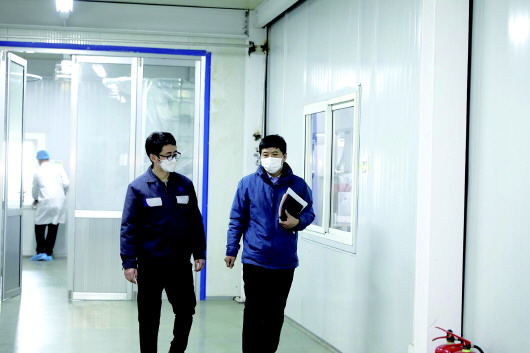 徐英亮(右)在和圣泉集团口罩生产车间主任交流.(受访者供图)