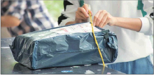 一位女士正在拆开新收到的快递包裹. (资料片)